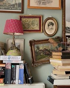 there are many pictures on the wall above this book shelf and lamp in front of them