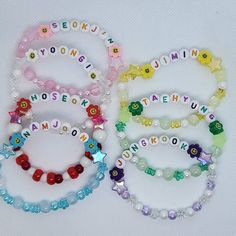 four bracelets with name charms on them sitting next to each other in different colors