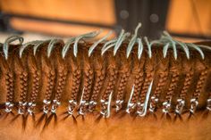 the hair is being braided by someone's hand with metal pins on it