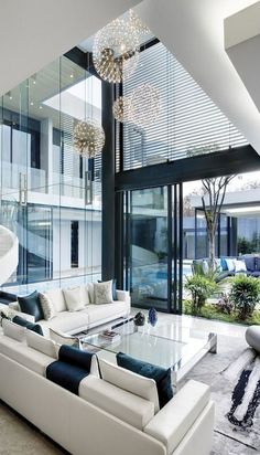 modern living room with white couches and chandelier in front of large windows