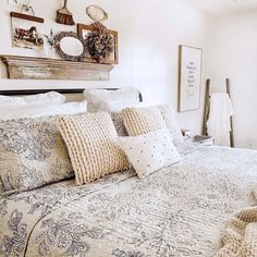 a bed with pillows and blankets on top of it in a bedroom next to a mirror