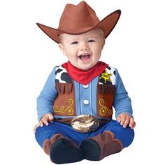 a baby sitting on the ground wearing a cowboy hat