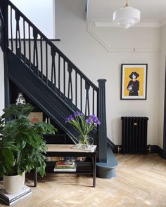 there is a plant on the table in front of the stair case next to the bookshelf