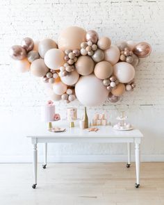 a table topped with lots of balloons on top of a white brick wall next to a wooden floor