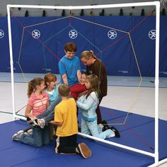 a group of young children sitting on top of a blue floor