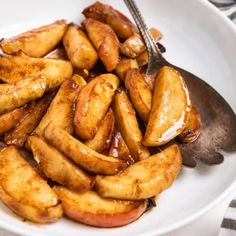 a white plate topped with apples covered in caramel glaze and sitting next to a fork