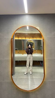 a person taking a photo in front of a mirror with a camera on the wall