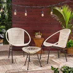 two white chairs sitting on top of a patio next to a table and potted plants