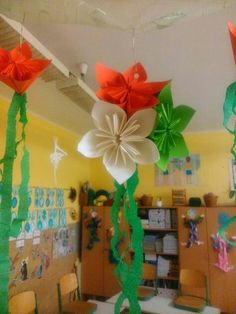 some paper flowers hanging from the ceiling in a room with desks and bookshelves