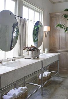 a bathroom with two sinks, mirrors and plants in baskets on the counter top next to each other