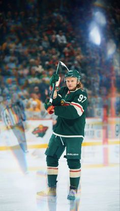 a hockey player holding a stick in front of an arena full of people and fans