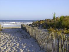 a wooden fence on the beach next to the ocean