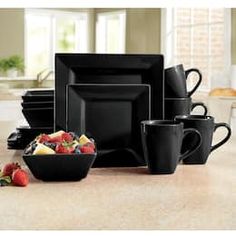 a table topped with black plates and bowls filled with fruit