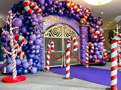 an entrance decorated with balloons and candy canes in front of a purple carpeted area