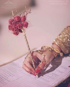 a close up of a person's hand holding a rose on top of a piece of paper