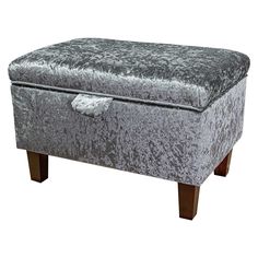 a grey velvet storage ottoman with wooden legs and feet rests on an isolated white background