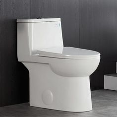 a white toilet sitting in a bathroom next to a black and white wall with wooden paneling