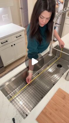 a woman measuring the drain in a kitchen sink