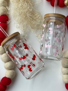 two glass jars with hearts painted on them next to red and white balls, yarn and other decorations