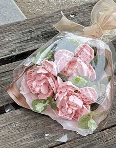 a bouquet of pink flowers sitting on top of a wooden bench