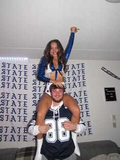 two cheerleaders are on top of each other in the middle of a room