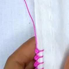 someone is stitching the end of a piece of white fabric with pink thread on it