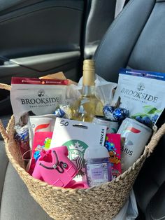 a basket filled with lots of items in the back seat of a car next to a bottle of wine