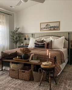 a bedroom with a large bed and lots of pillows on the headboard, along with wicker baskets