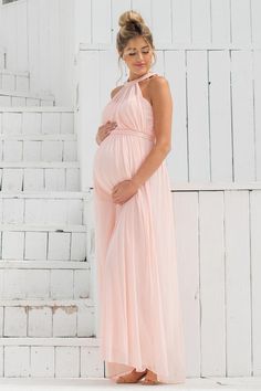 a pregnant woman in a pink dress standing on steps with her belly tucked under her stomach