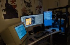 three computer monitors sitting on top of a desk next to a keyboard and monitor screen