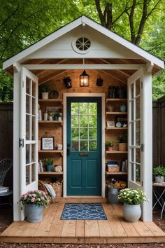 a small wooden shed with potted plants on the front door and shelves full of books