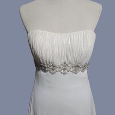 a white dress on a mannequin dummy with silver beaded trimmings