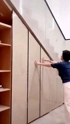 a man climbing up the side of a set of stairs next to a book shelf