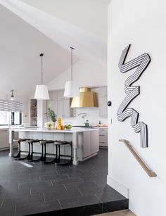 a kitchen with white cabinets and black tile flooring next to a wall mounted clock