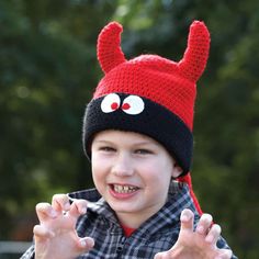 a young boy wearing a red and black knitted hat with an antler on it