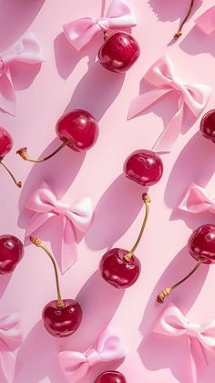 cherries are arranged on pink paper with bows