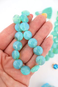 a person is holding some blue beads in their hand