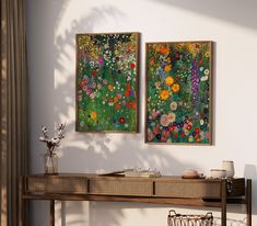 two paintings hang on the wall next to a console table with vases and flowers