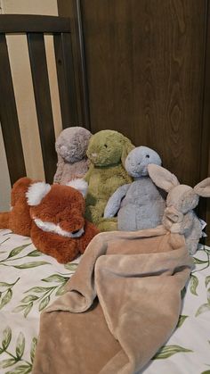 four stuffed animals sitting on top of a bed