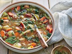 a bowl of soup with carrots, broccoli and other vegetables in it