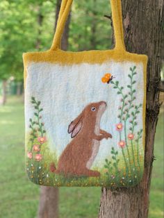 a handbag hanging from a tree in the grass with a brown bunny on it