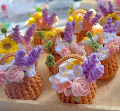 small crocheted baskets filled with flowers on top of a cloth covered tablecloth