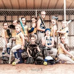 a group of young women standing next to each other in front of a baseball cage