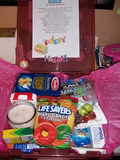 an open suitcase filled with candy and other items next to a birthday card on top of a table