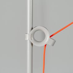 an orange cord connected to a white pole with a circular object on it's end