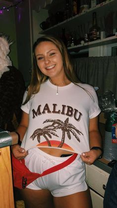 a woman in white shirt and shorts standing next to a stuffed animal on top of a counter