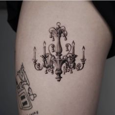 a black and white photo of a chandelier tattoo on the back of a woman's thigh