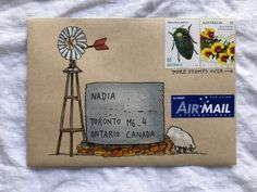 a postcard with an image of a windmill and flowers on it, next to a mailbox