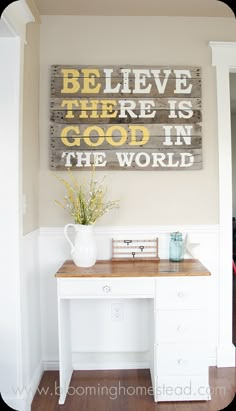 a wooden sign that says believe there is good in the world above a white desk