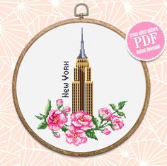 the empire building is shown in this cross stitch pattern, with pink flowers on it